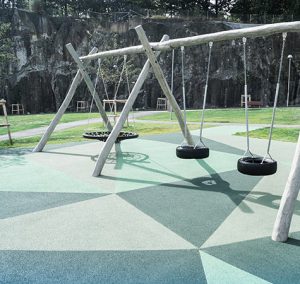 Playground with swings on a safety surfacing with Genan Color-coated Granulate