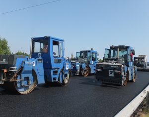 Workers in Asphalt rollers lay a new road